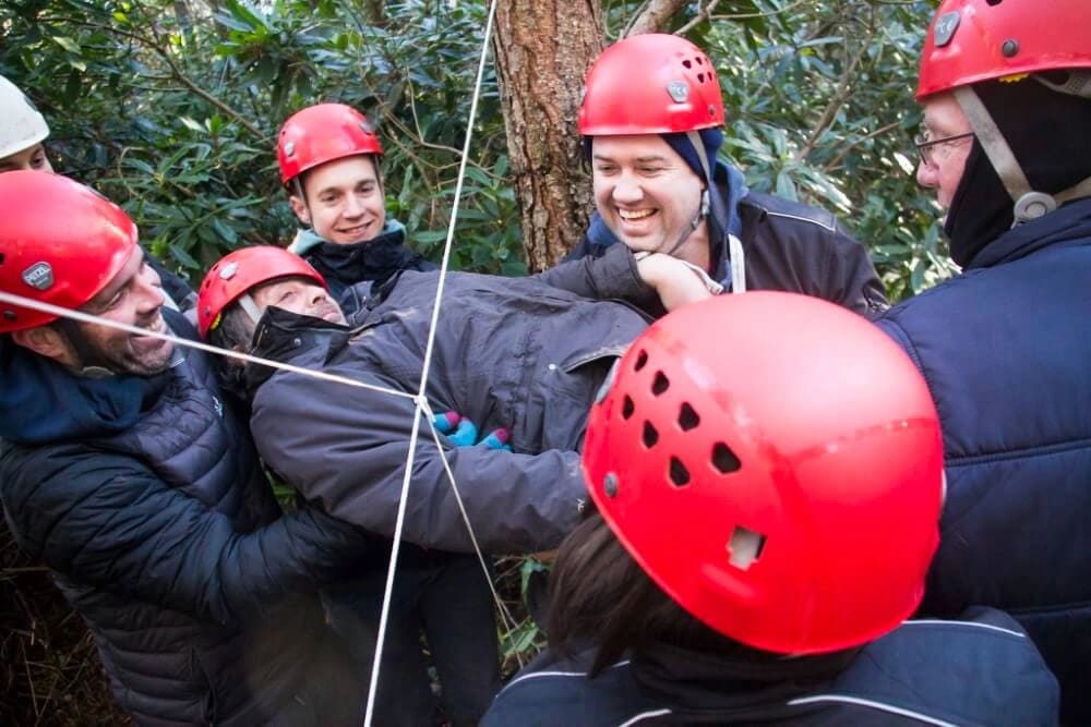 A group of men taking part in a team building exercise with ropes at New Forest Activities